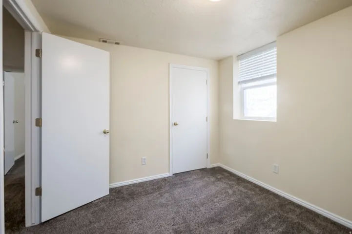 Plush carpet flooring, neutral paint palette, white trim work, and a window with blinds