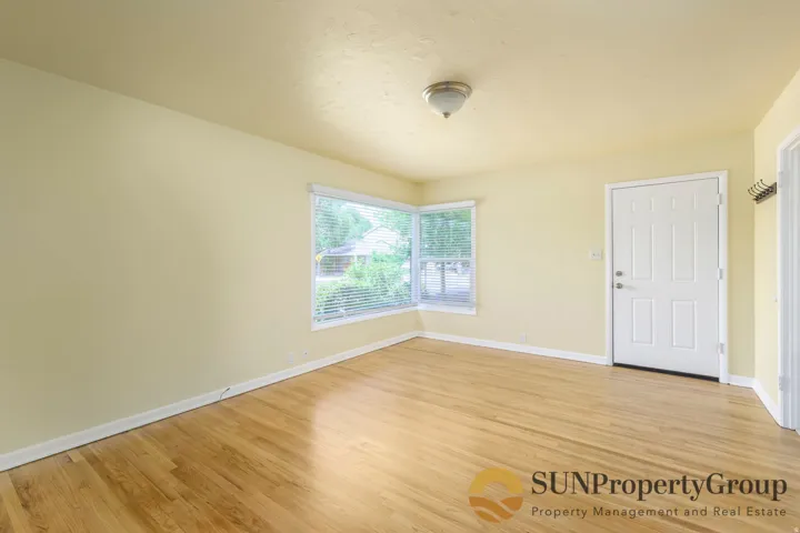 Wood-finish flooring throughout, light-toned wall paint, and a bright corner window
