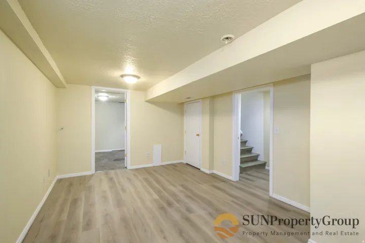Spacious room featuring wood-finish flooring, recessed lighting, and a white interior door
