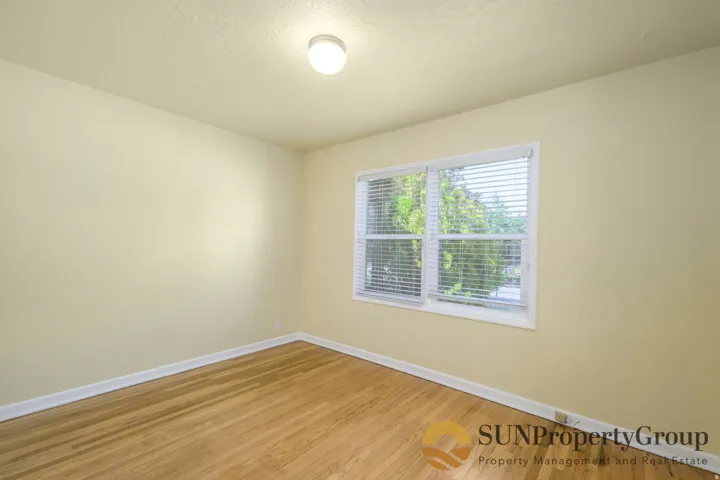 Wood-finish flooring, neutral wall tones, and a window with horizontal blinds provide a bright interior