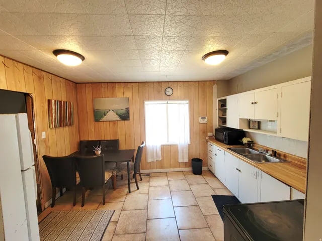 Kitchen featuring wood paneling, tile flooring, white cabinetry, and wood-finish countertops