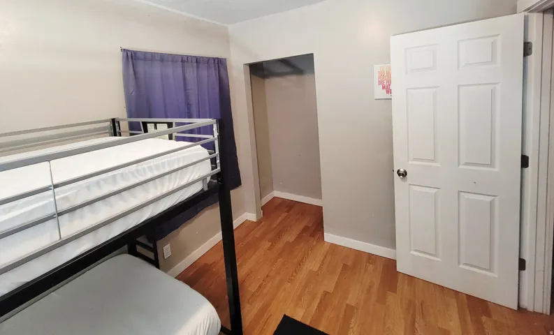 Hardwood-finish flooring, white trim, and a six-panel interior door