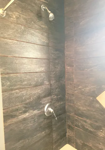 Shower enclosure with wood-finish tile walls and chrome fixtures