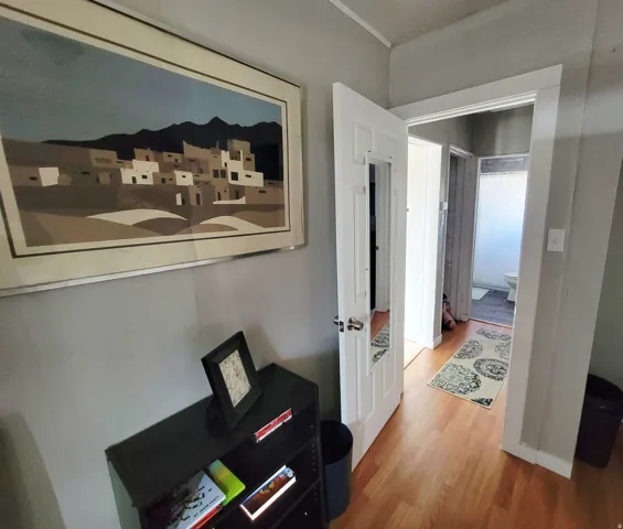 Wood-finish flooring throughout, white trim, and a paneled interior door