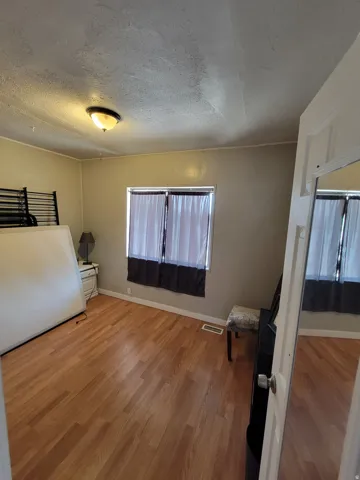 Wood-finish flooring throughout, ceiling-mounted light fixture, and window with opaque coverings