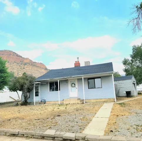 Light blue vinyl-sided home featuring a pitched roof with dark shingles, brick chimney, and covered front porch