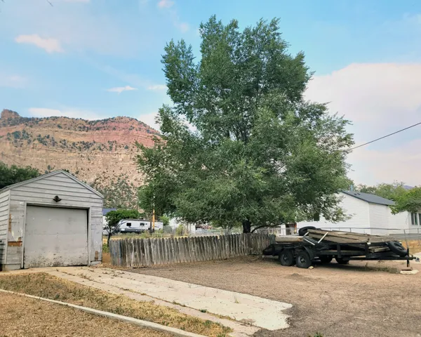 Detached garage with horizontal siding, a wood fence, mature tree, and a mountain backdrop