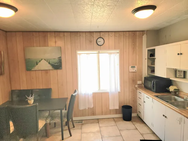 Wood-finish wall paneling, tiled flooring, white cabinetry, and wood-finish countertops