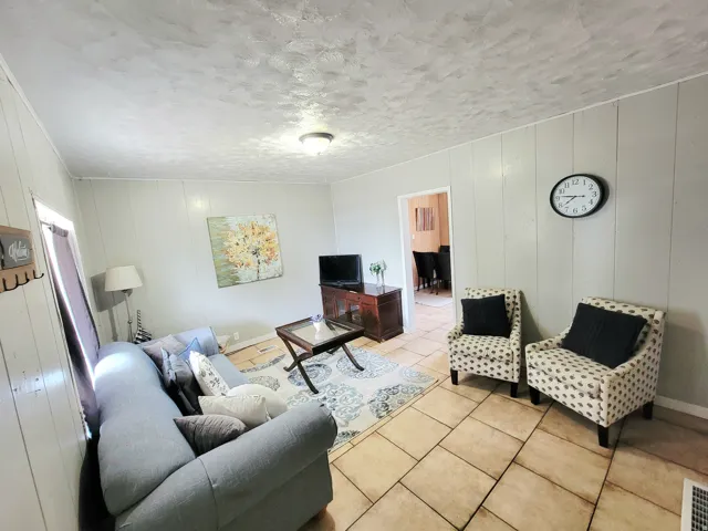 Warm living area featuring light-toned paneling, recessed lighting, and tile flooring