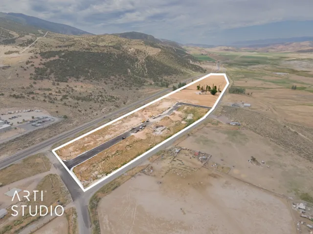 Extensive land parcel featuring a paved access point, established trees, and surrounding undeveloped terrain