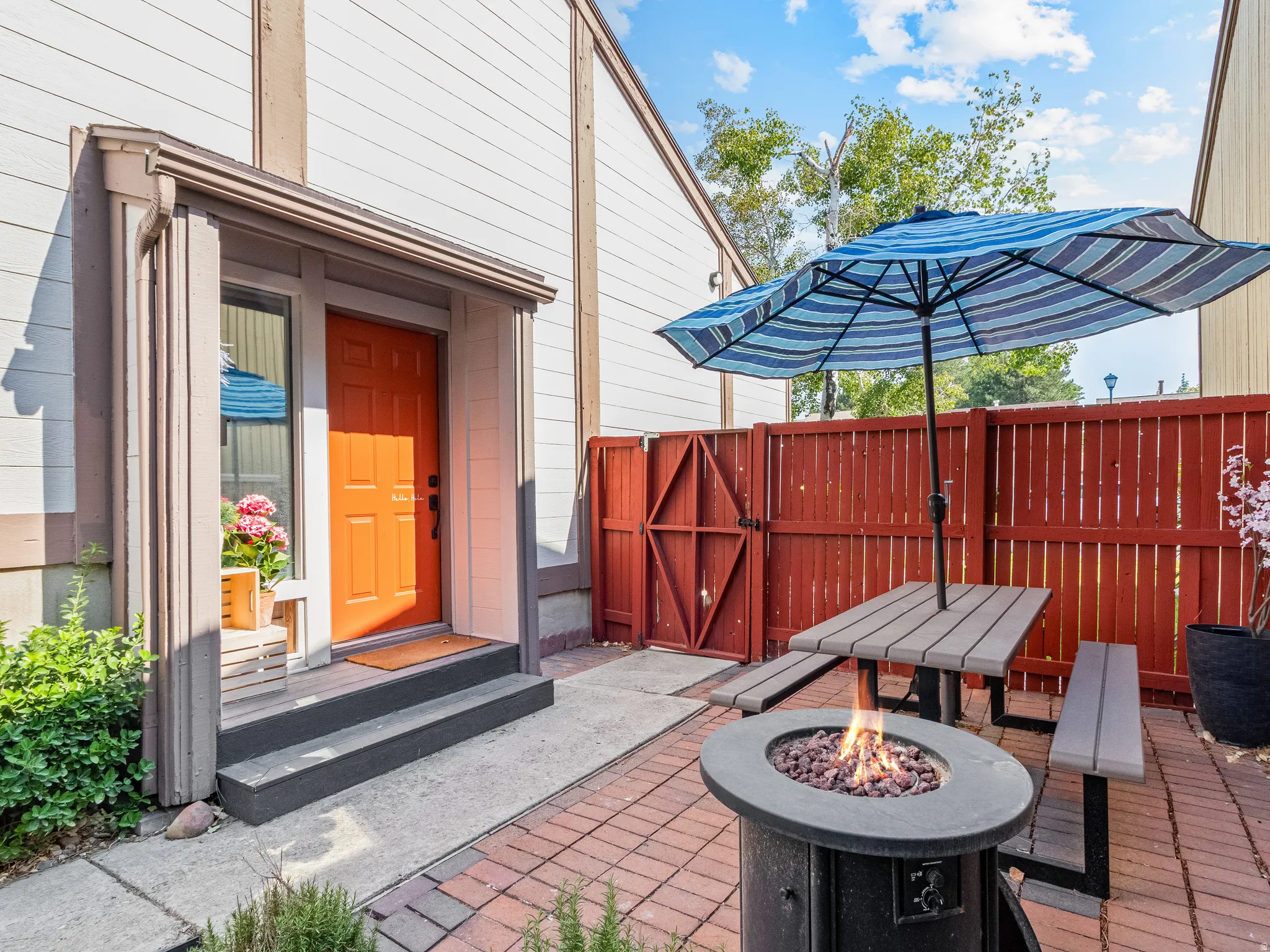 Brick paver patio, wood privacy fence, entry door with sidelight, exterior fire pit, and durable siding