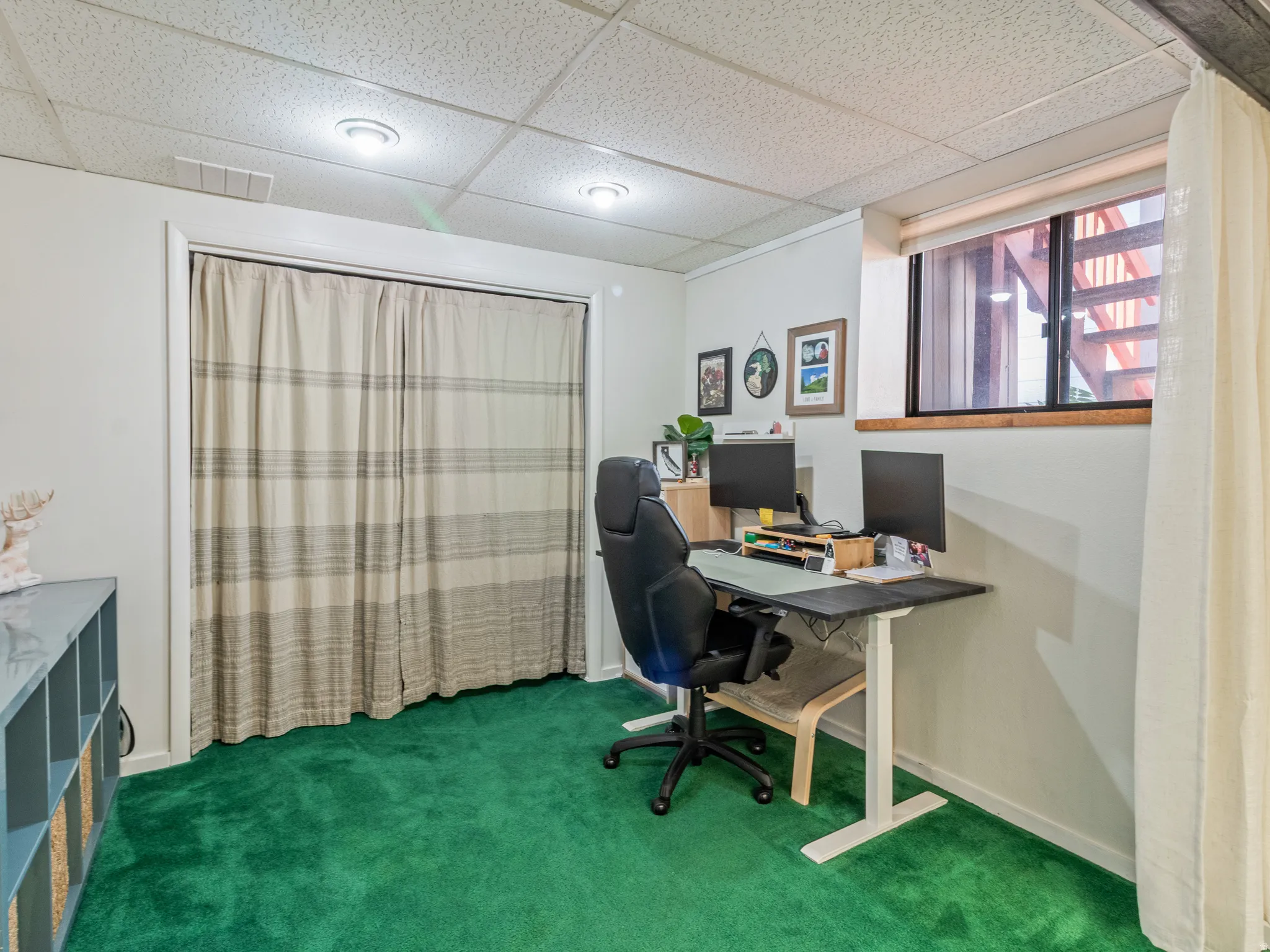 Recessed lighting illuminates a space featuring green carpeting and a drop ceiling