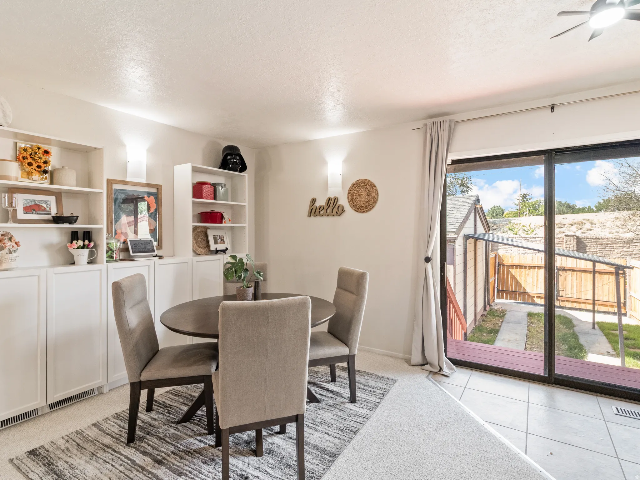 Built-in shelving and cabinetry, sliding glass door, outdoor patio, tiled flooring, and ceiling fan