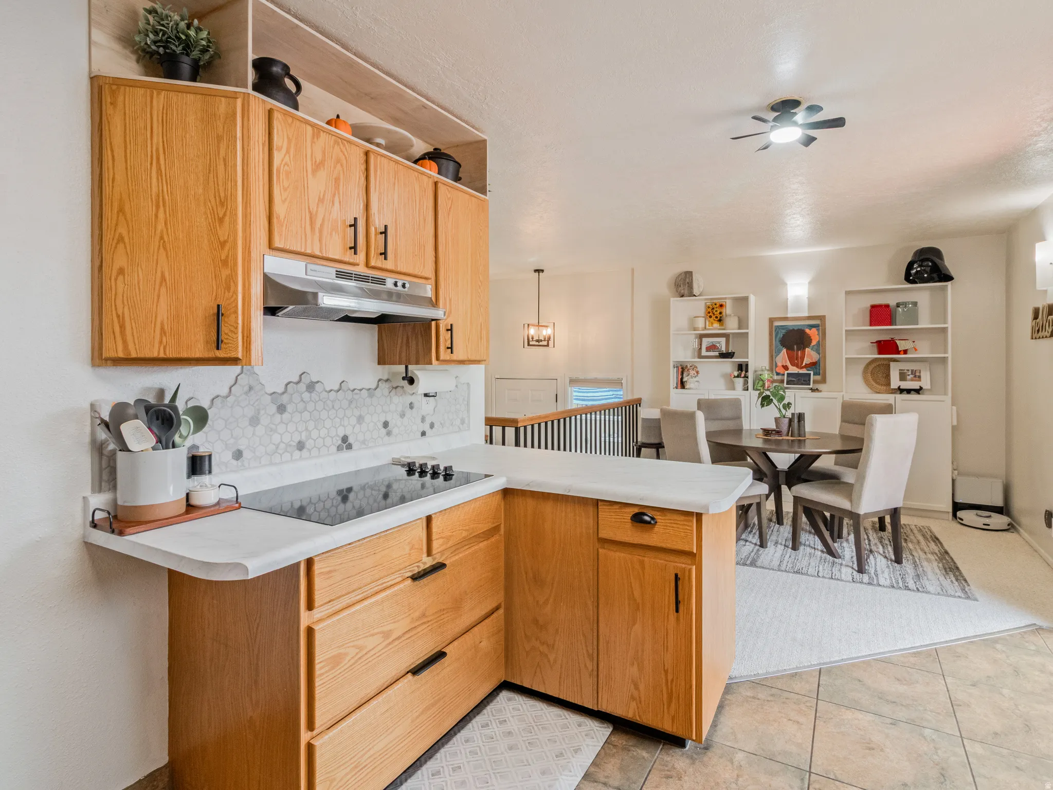 Kitchen features wood cabinetry, white countertops, and a hexagonal tile backsplash