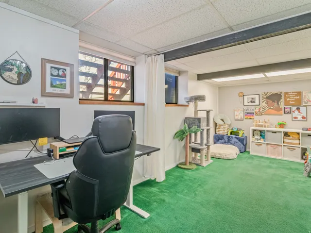 Room with green carpet flooring, white walls, and a drop ceiling