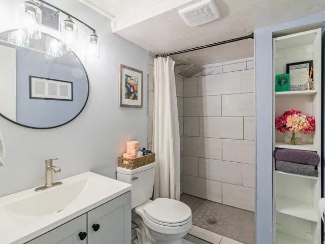 Shower with light-toned rectangular wall tiles and hexagonal floor tiles