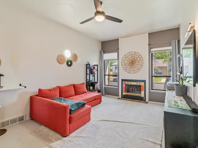 Recessed fireplace with a gold-toned surround, flanked by two large windows with roller shades and drapery
