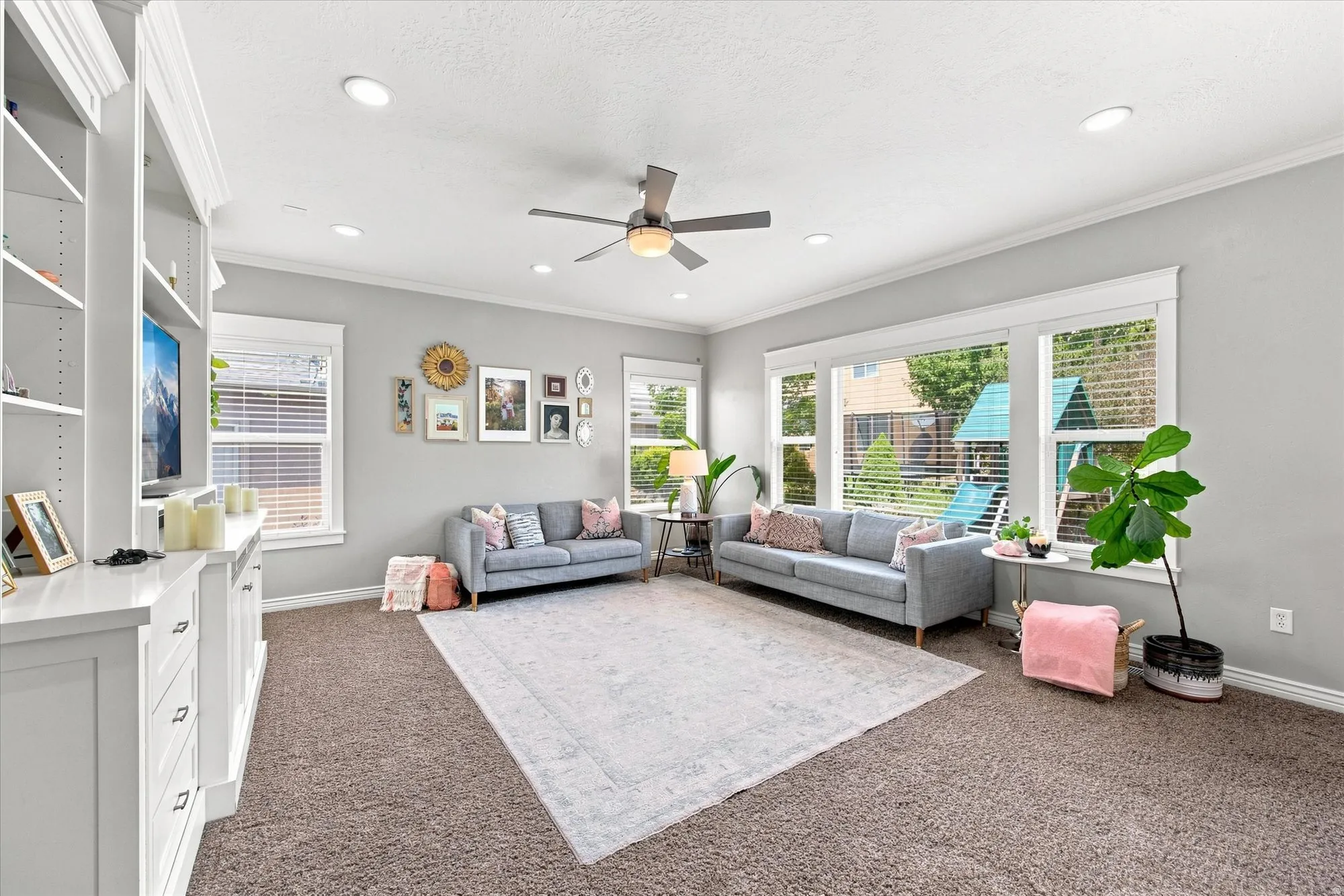 Built-in cabinetry with open shelving, recessed lighting, ceiling fan, and multiple windows with blinds