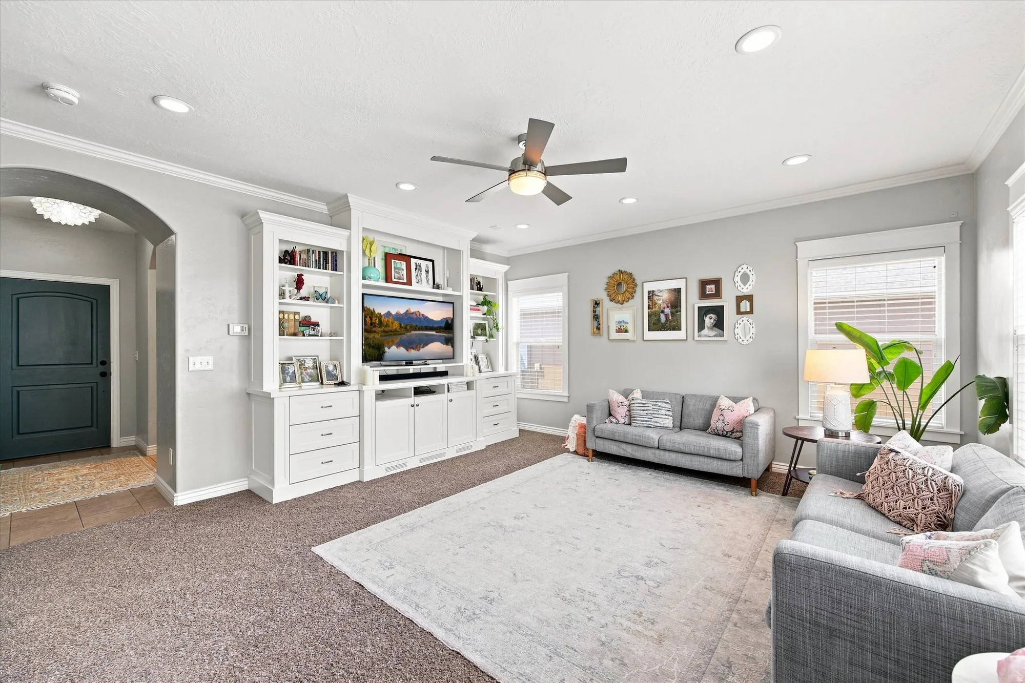 Integrated built-in cabinetry with shelving, recessed lighting, ceiling fan, crown molding, and multiple windows with blinds