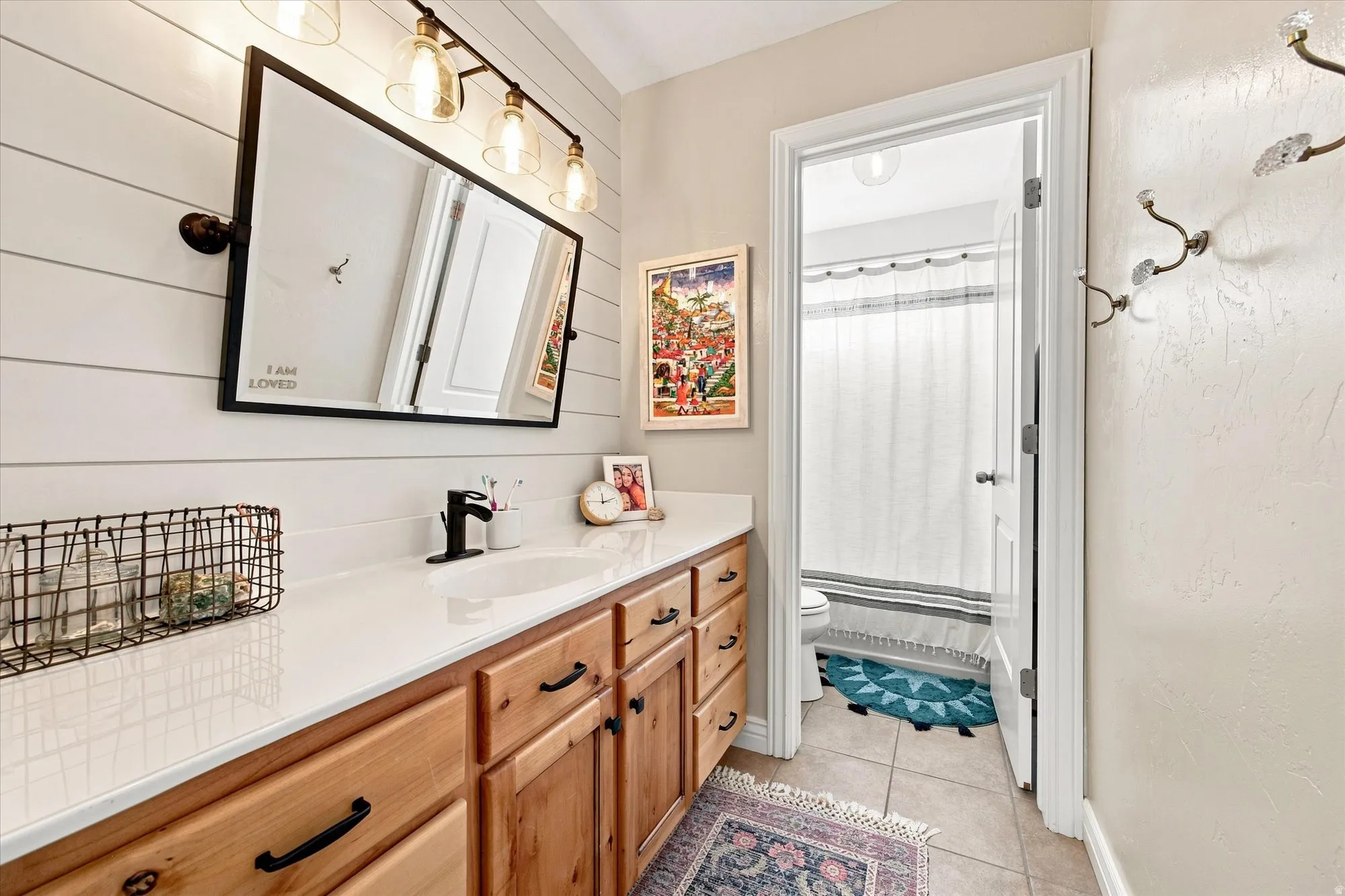 Vanity with light wood cabinetry, white countertop, and integrated sink