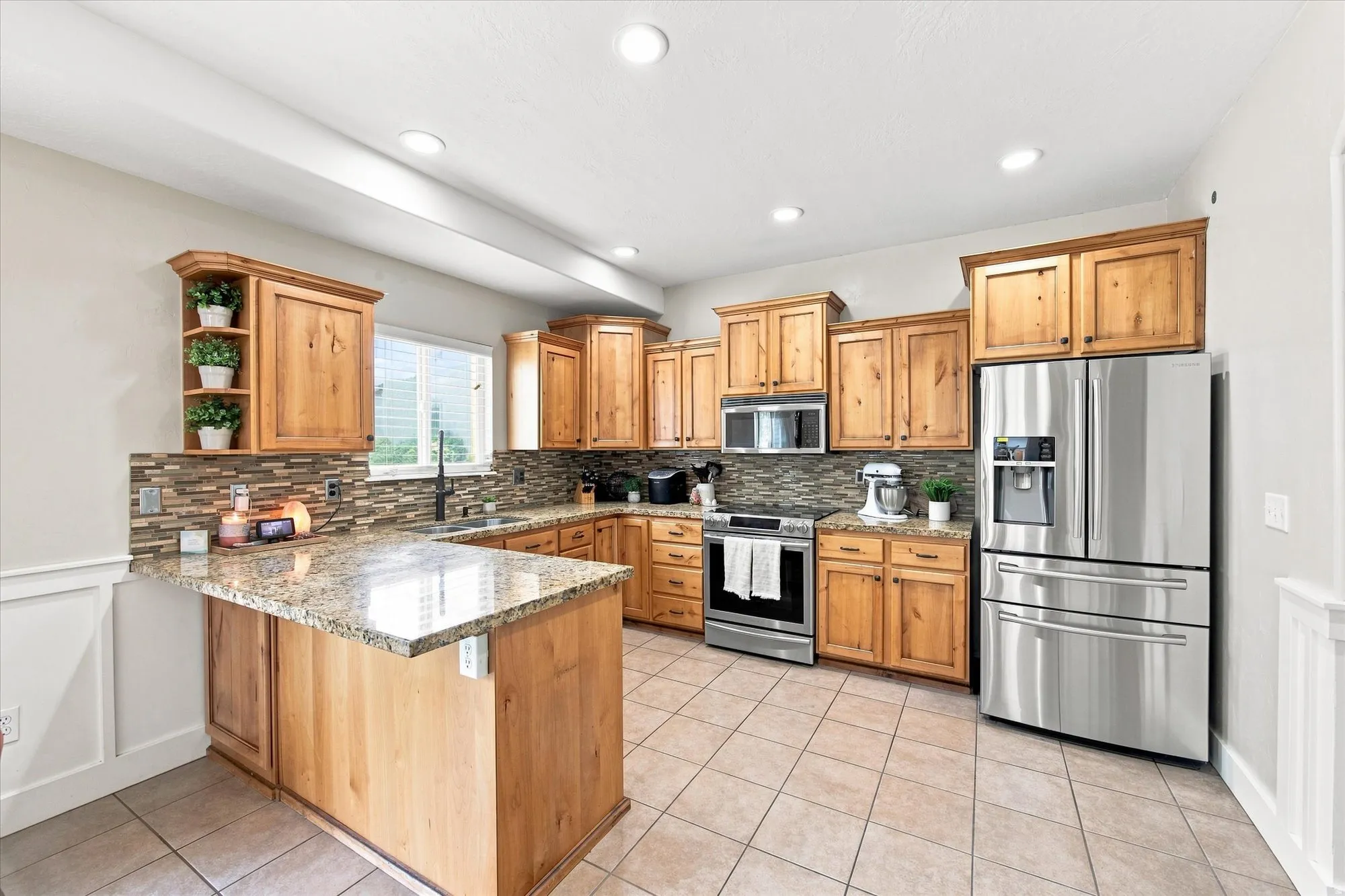 Kitchen featuring stainless steel appliances, wood-finish cabinetry, granite countertops, and a tiled backsplash