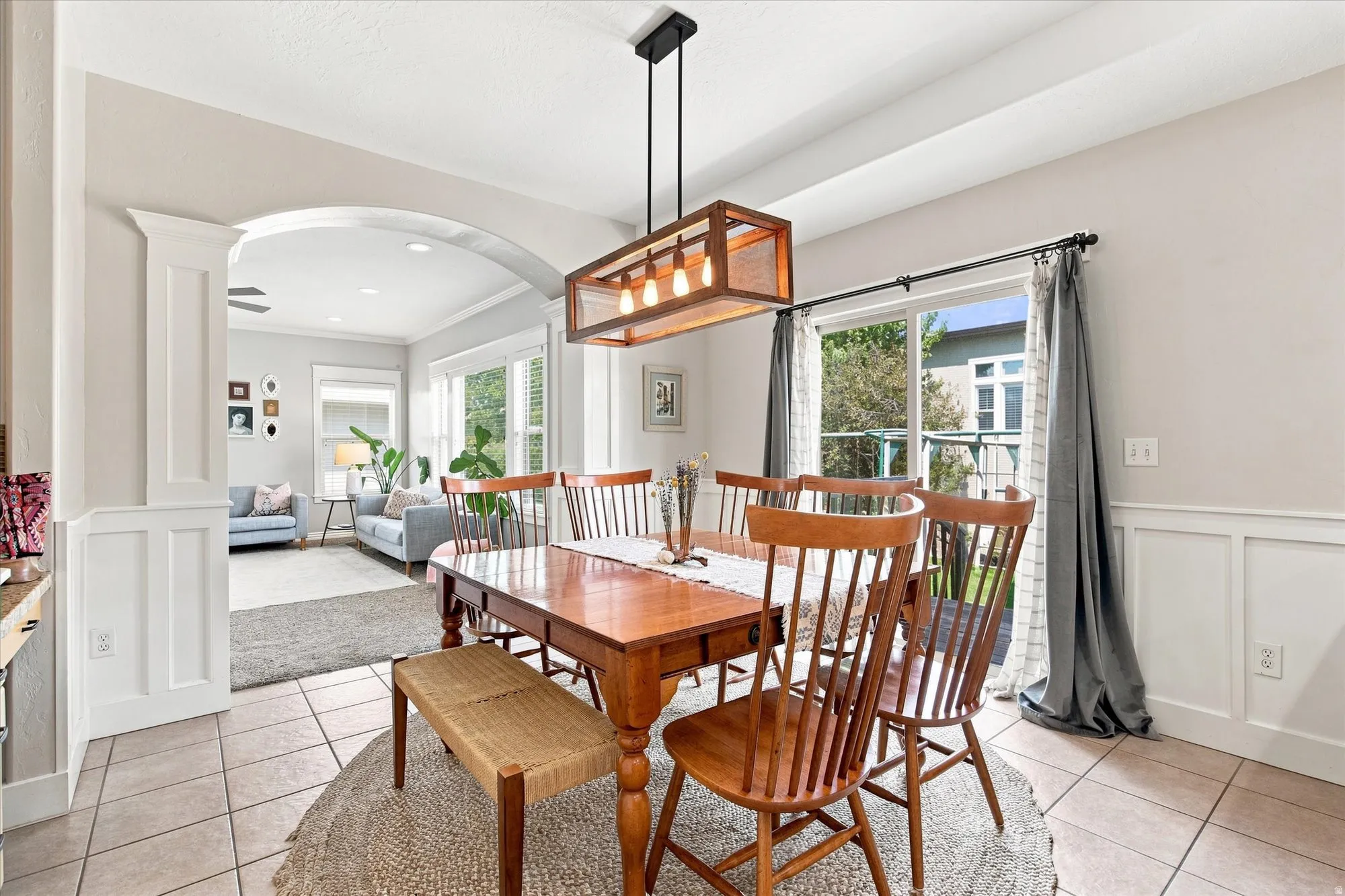 Tiled flooring with a rectangular wood dining table, accented by a wood-framed linear chandelier