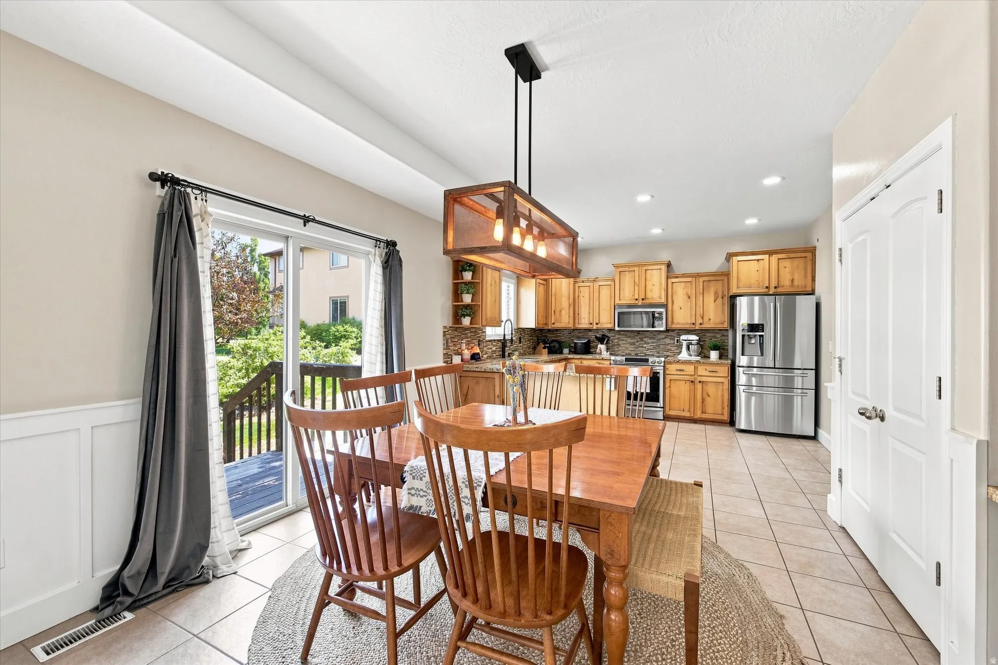 Sliding glass door, wood-finish cabinetry, stainless steel appliances, tile flooring, recessed lighting