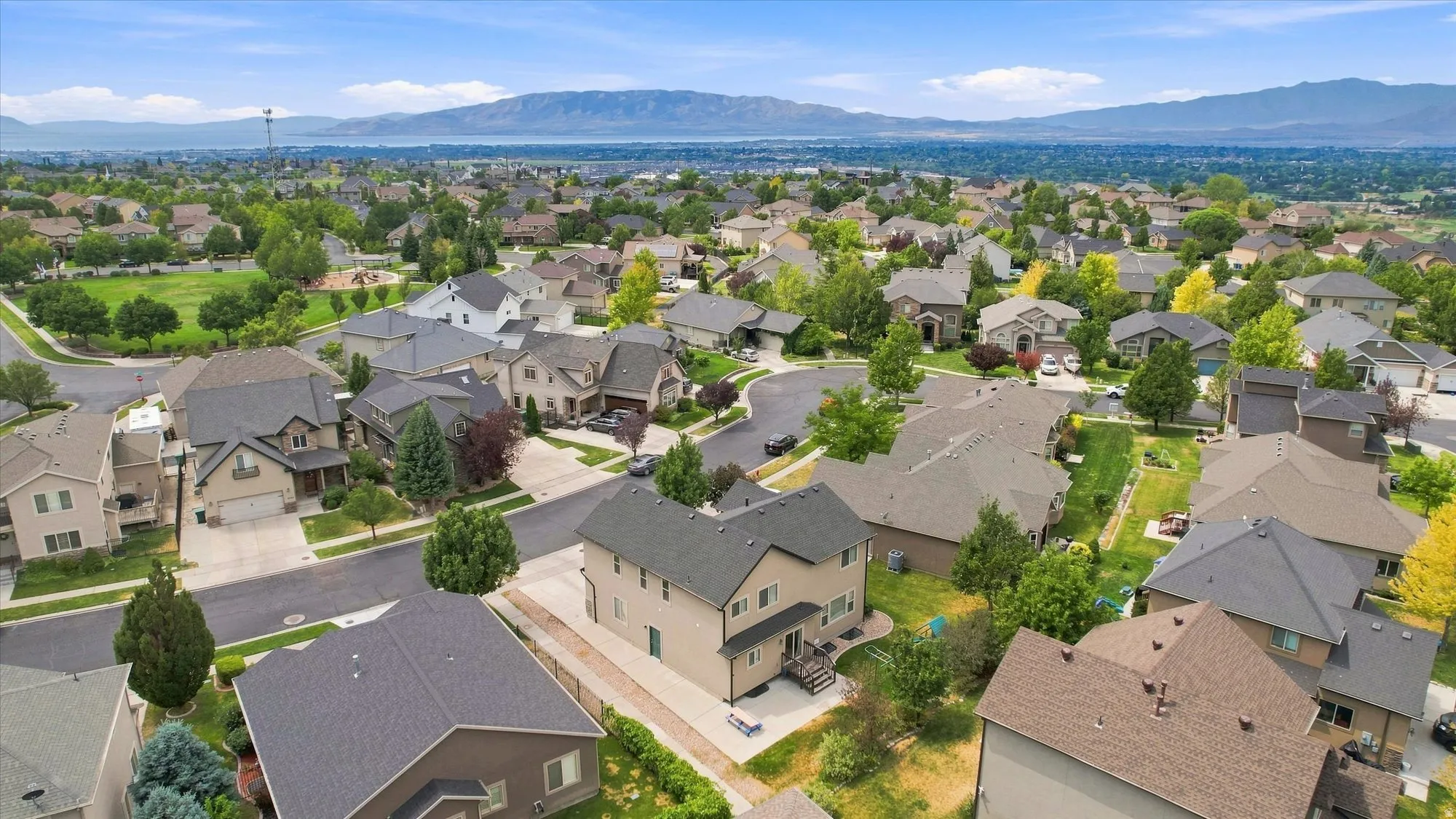Suburban neighborhood with mature trees, green spaces, and mountain scenery