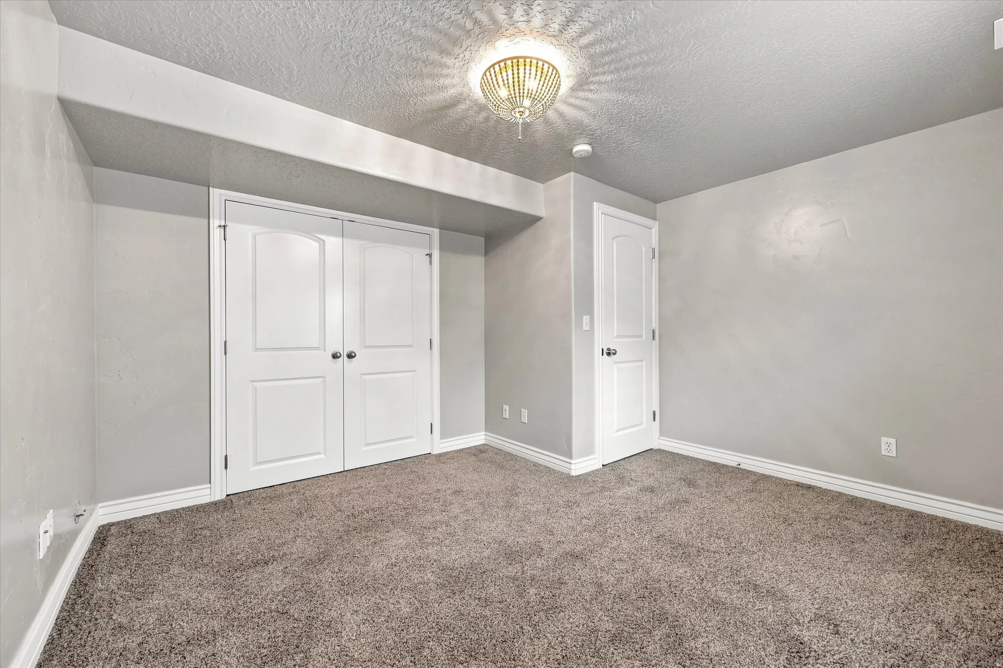 Plush carpeting, neutral wall finishes, white trim, traditional panel doors, and a decorative ceiling light fixture