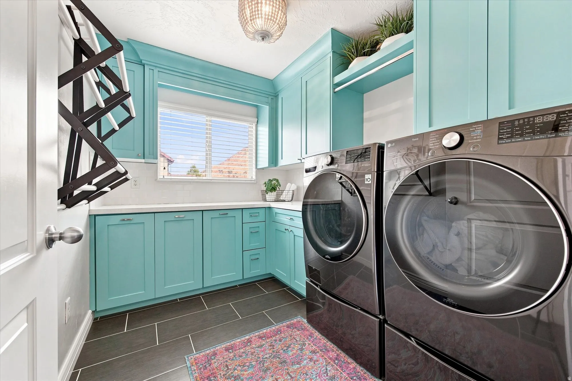Turquoise cabinetry with built-in shelving, white countertop, and dark rectangular floor tiling