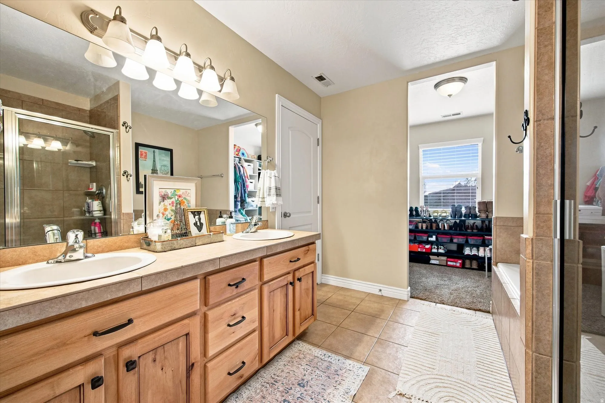 Primary bedroom ensuite bathroom Dual sink vanity with wood-finish cabinetry and tile countertop