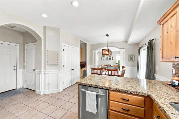 Recessed lighting, wood-finish cabinetry, stainless steel dishwasher, tile flooring, and a stone countertop