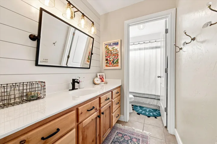 Vanity with light wood cabinetry, white countertop, and integrated sink