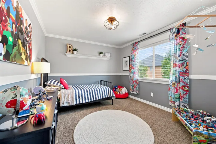 Crown molding, two-tone wall treatment, built-in shelving, window with blinds, and ceiling-mounted light fixture