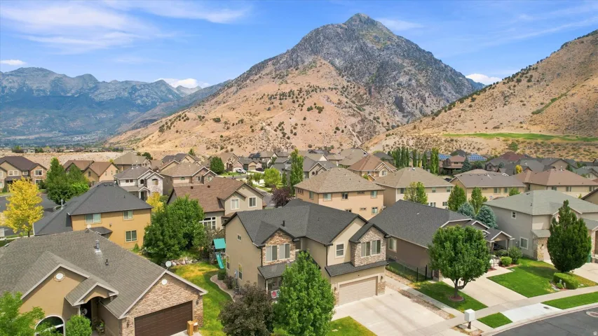Residential neighborhood with varied architectural styles and mature trees, set against a mountainous backdrop