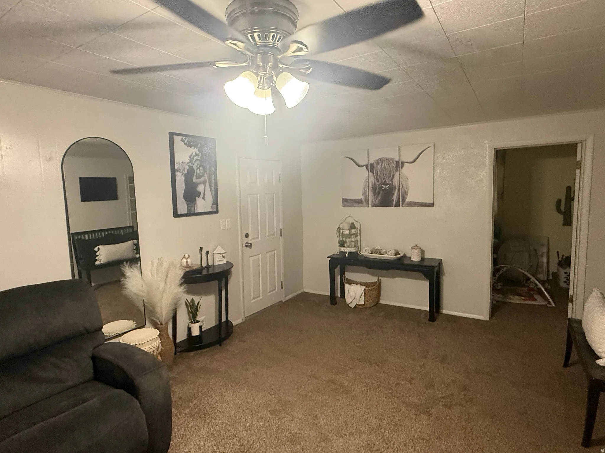 Recessed ceiling with an attached ceiling fan, arched doorway, and interior paneled door