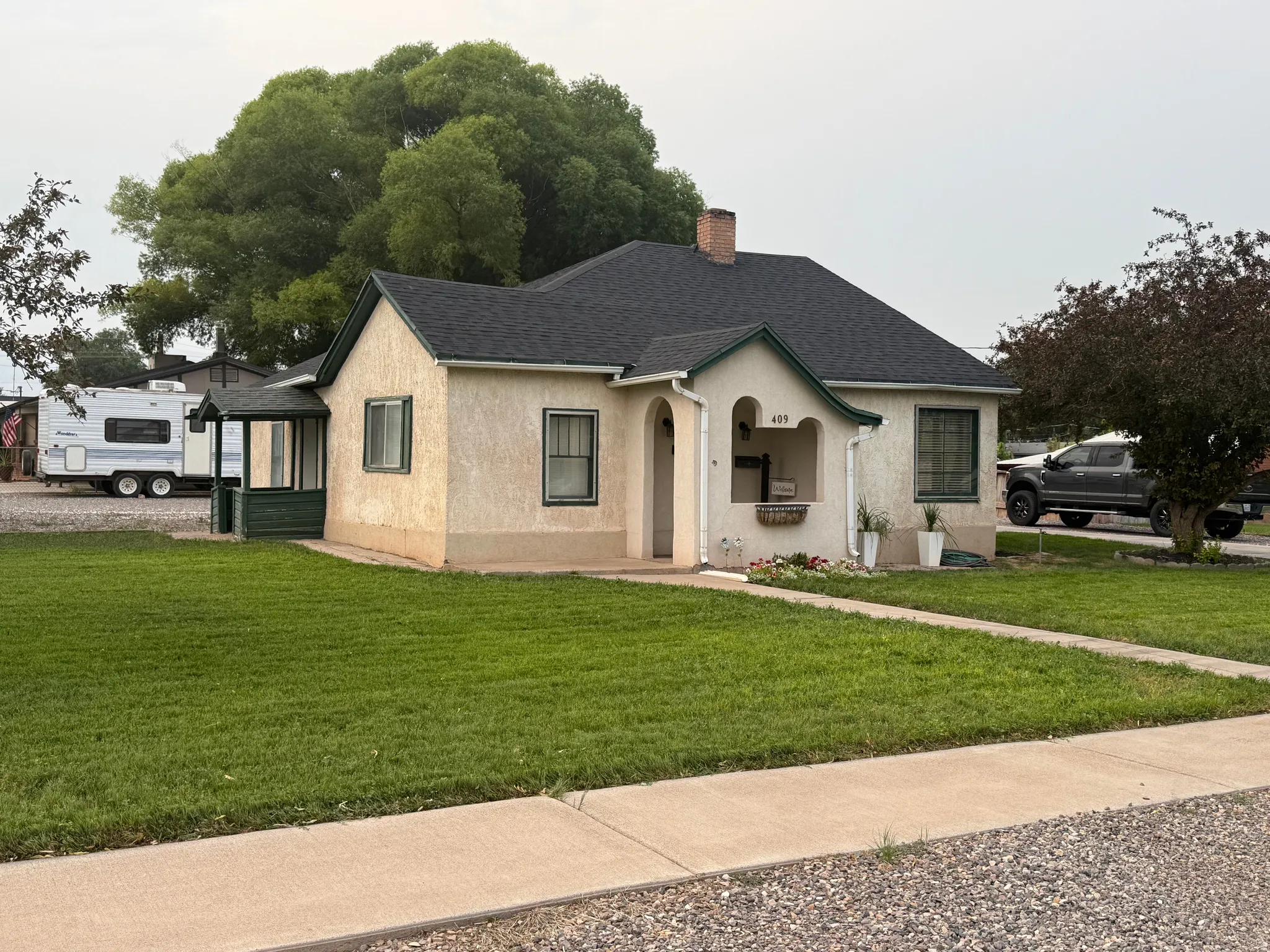 Stucco exterior with dark trim accents, covered front entry, and a covered side porch