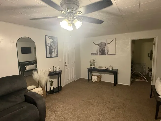 Recessed ceiling with an attached ceiling fan, arched doorway, and interior paneled door
