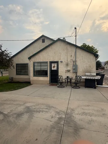 Stucco exterior with a dark trim, concrete patio area, and a large paved driveway