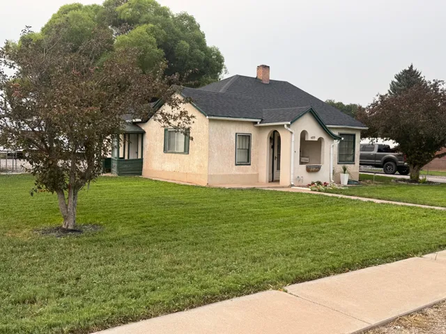 Stucco exterior with a covered entry, established landscaping, and a manicured lawn