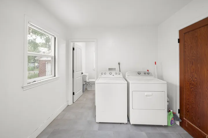 Laundry area with tiled flooring, white walls, and a white-framed window