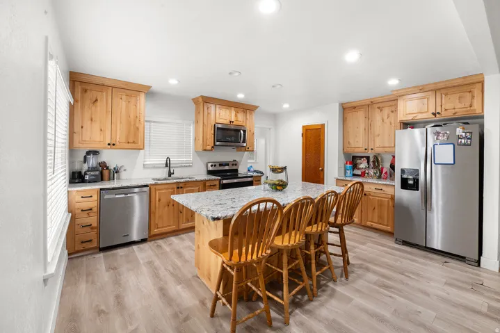 Wood-finish flooring, recessed lighting, wood cabinetry, stone countertops, and stainless steel appliances
