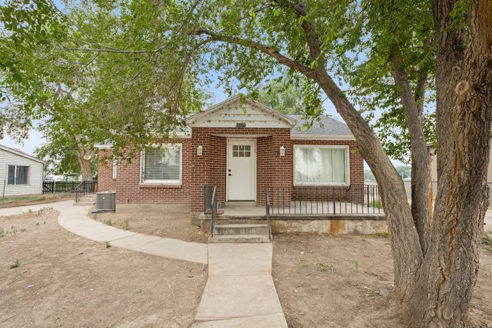 Brick exterior with a white entry door, covered front porch, and a concrete pathway