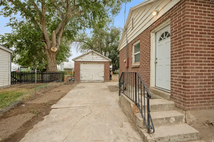 Brick exterior with white trim, concrete steps with wrought iron railing, and a white entry door with an arched window detail