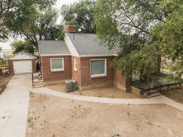 Brick exterior residence featuring an attached chimney, asphalt shingle roof, and an exterior AC unit