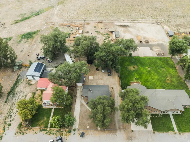 Expansive property featuring multiple structures, mature trees, a detached garage with solar panels, and a large grassy area