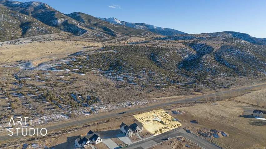 Mountainous terrain backdrop, expansive land area, adjacent roadway, visible residential properties