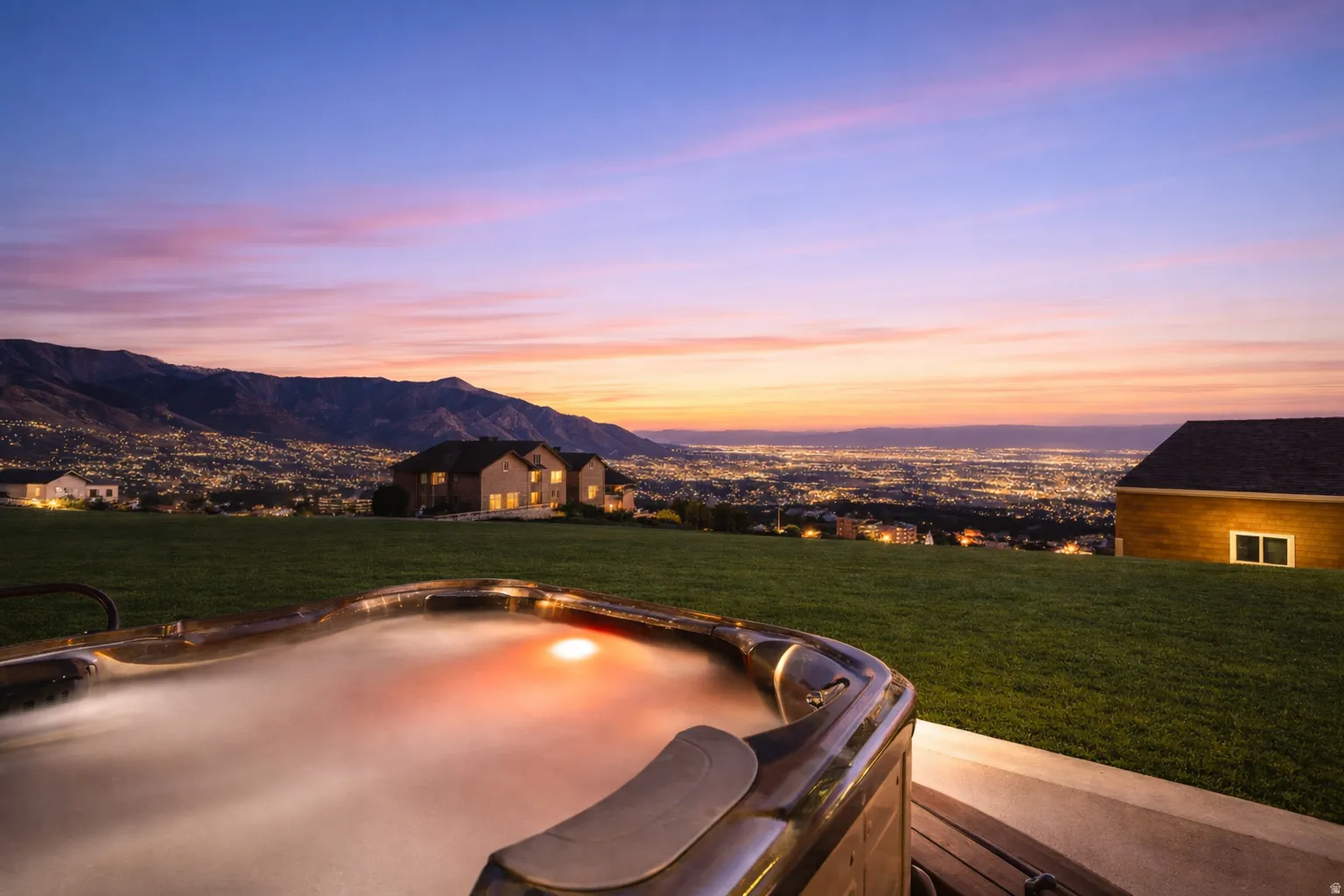 Integrated hot tub with exterior lighting, concrete patio, and sloped lawn