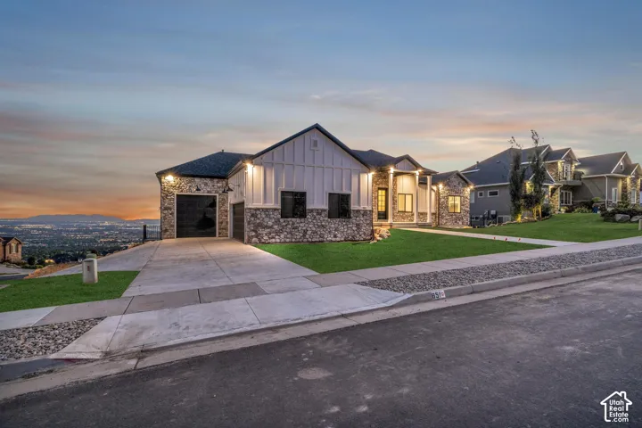 Stone and board-and-batten exterior with a two-car garage, concrete driveway, and manicured lawn