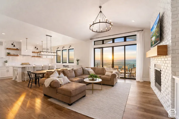 Open-concept living space featuring a large sectional arrangement, hardwood flooring throughout, and expansive glass sliding doors opening to a covered balcony with scenic outlooks